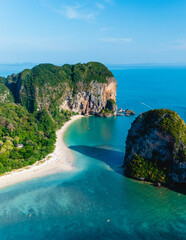 Golden sands meet vibrant turquoise waters at Railay Beach Krabi Thailand, surrounded by majestic cliffs under a bright blue sky. This tropical paradise offers relaxation and stunning views