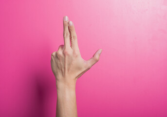 Asian hand mimicking a finger gun gesture with thumb raised and two fingers pointed forward on a...