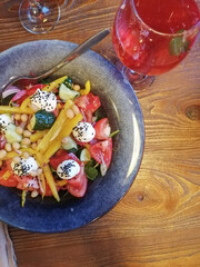 a signature vegetable salad sits on the table next to a glass of berry lemonade