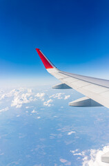 View from the airplane window at a beautiful cloudy sky and the airplane wing