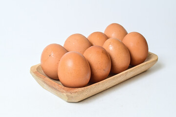 Close up fresh raw chicken eggs placed in long wooden plate. Isolated on white background.