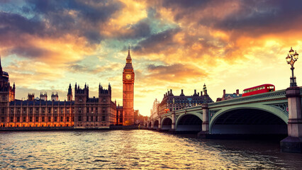 Naklejka premium An iconic view of Big Ben and the Houses of Parliament at twilight, with golden lights reflecting on the River Thames