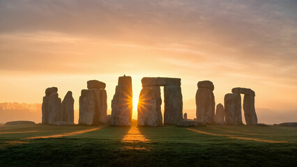 A high-resolution sunrise shot of Stonehenge, with golden light casting long shadows over the ancient stones