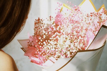 Close-up of a woman holding a beautiful bouquet of pink baby's breath flowers