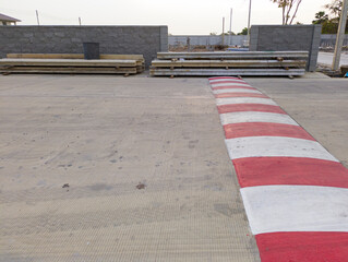 The main street of a village under construction features a red and white speed bump designed to...
