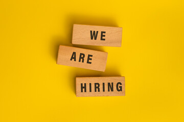 we are hiring words on wooden blocks isolated on yellow background
