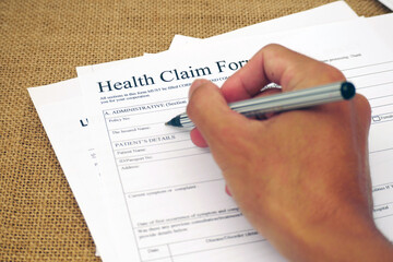 Hands filling out health claim form