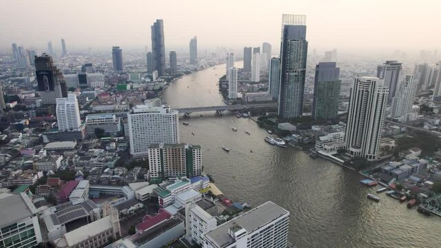 Bangkok high aerial view of the Chao Phraya River at Si Lom districts at sunset. A large asian capital city with skyscrapers and millions of inhabitants. Beautiful Cinematic 4k footage 2025