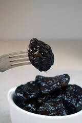 Close-Up of Fork Holding Soft Dried Prune Over a Bowl. Delicious Natural Food Ingredient for Cooking, Baking, and Nutritious Eating with Sweet and Juicy Texture