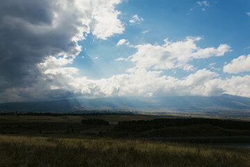 landscape with mountains, sun rays and clouds