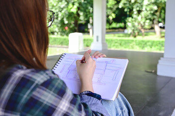 Rear view young architect collage student sketching floor plan on sketchbook at outdoor class