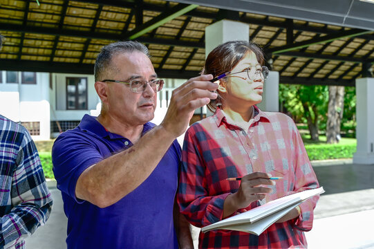 Senior art teacher teaching artist girl to paint in outdoor art class