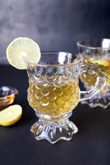 A glass cup of fresh lemon tea with lemon, honey and green mint leaves. copy space. Herbal tea. Weight loss journey. A warm cup of honey lemon tea with fresh lemon slices and a drizzle of honey.