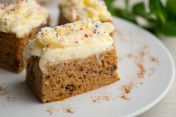 Small slices of carrot cake with a cream cheese frosting and caramel balls for decoration.