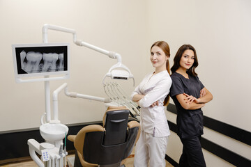 Smiling dentist and assistant with crossed hands looking at the camera in dental clinic