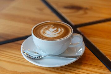 coffee latte art on wood table in cafe nature light
