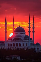 Fototapeta premium A vast mosque with elegant domes is outlined against a fiery orange sunset. The sky shifts into deep red as twilight sets in