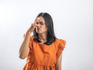 Asian woman in orange ruffled blouse pinching her nose with a disgusted facial expression, reacting...