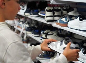 children and clothing and footwear shopping concept. child choosing a pair of sneakers