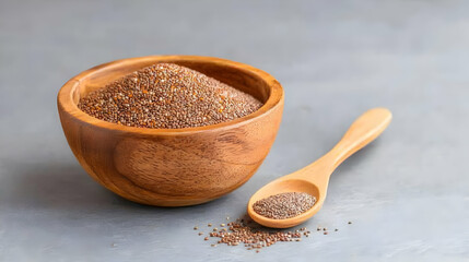 Brown mustard seeds in wooden bowl with wooden spoon on gray background