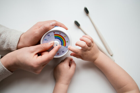 Adult and child using toothbrushing timer with colorful dial for dental hygiene