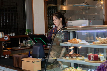Asian barista female making hot coffee from professional machine standing behind cafe shop counter bar, young waitress worker or small business entrepreneur wearing apron working in eatery cafeteria