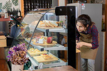 Asian young small business owner female service customer ordering using POS cash machine in cafe coffee shop restaurant, barista waitress worker standing in counter bar working in cozy workplace