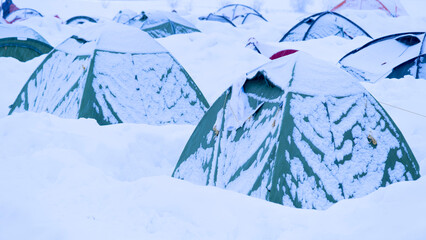 Colorful camping tents covered in snow after a snowstorm.