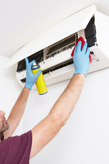 Man cleaning and maintaining air condition unit at home.
