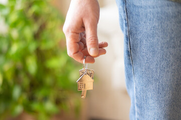 Real estate agent holding house keys adorned with a house-shaped keychain, celebrating the...