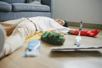 Portrait Of Young Man Lying On The Floor, Sleeping With Cleaning Tools During Home Chores