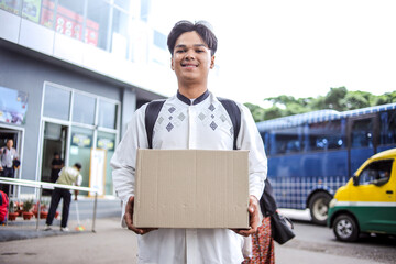 Young Muslim Man Holding Cardboard Box Ready to Going Home or Mudik for Eid Mubarak