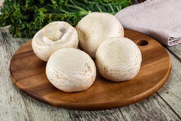 White champignon mushrooms heap over board