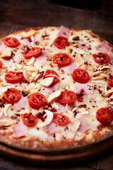 Pizza with ham, cherry tomatoes and mozzarella cheese. Wooden background. Soft focus. Close up.