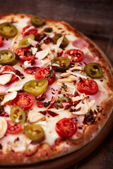 Pizza with ham, cherry tomatoes and mozzarella cheese. Wooden background. Soft focus. Close up.