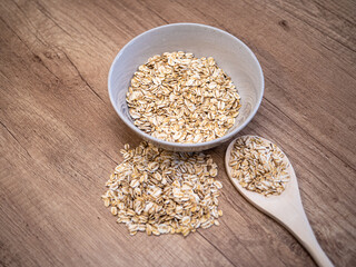 A bowl filled with rolled oats on a wooden countertop. A staple ingredient for healthy breakfasts and meal prep.