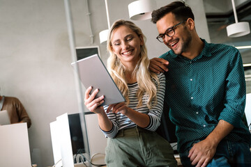 Young manager talking with experienced colleague while using computer in office.
