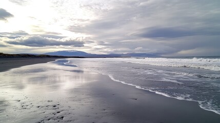 Obraz premium A tranquil beach landscape featuring clouds and distant mountains