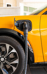 Fast EV charging station. Close-up of EV charging plug inserted into electric car at charging...