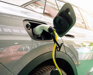 Diagonal view of EV charging plug inserted into electric car