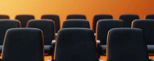 Fototapeta premium A row of black chairs against a warm orange background, creating a sense of depth and perspective.