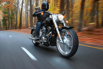 Obraz premium A motorcyclist speeds along a winding forest road, surrounded by vibrant autumn colors on a sleek black chrome bike