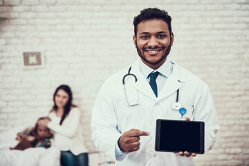 Indian doctor seeing patients at home. Doctor is posing with tablet with pregnant mother and...
