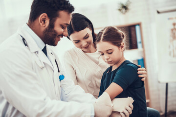 Indian doctor seeing patients in office. Doctor is using harness on daughter's arm.