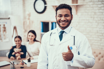 Indian doctor seeing patients in office. Doctor is posing giving thumbs up.