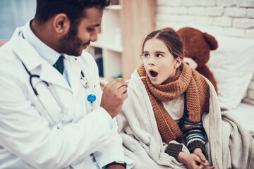 Indian doctor seeing patients at home. Doctor is examining throat of little girl with cold.
