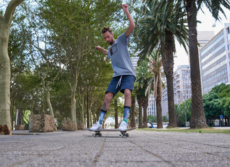 Obraz premium Skateboard, fitness and urban with man in city for culture, extreme sports and trick flip. Path hobby and street league with person training downtown for skating, ollie grind and balance practice