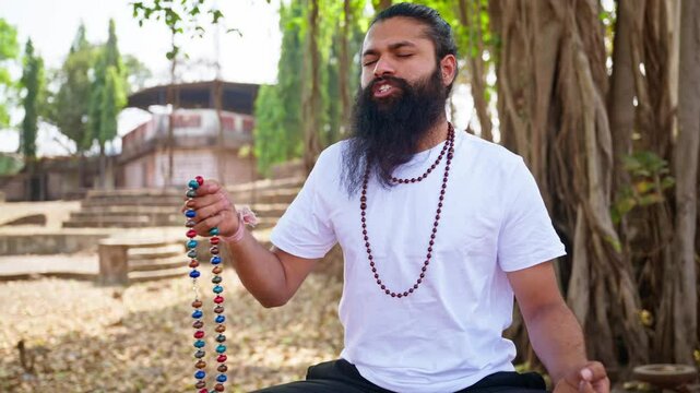 Mindful devotee sits praying and moving holy charms