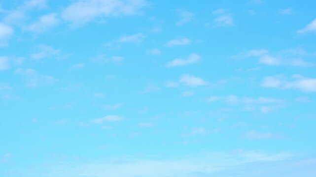 A time lapse video of tranquil expanse of light blue sky stretched endlessly, adorned with a few delicate, wispy clouds that add a touch of serenity to the vastness.
