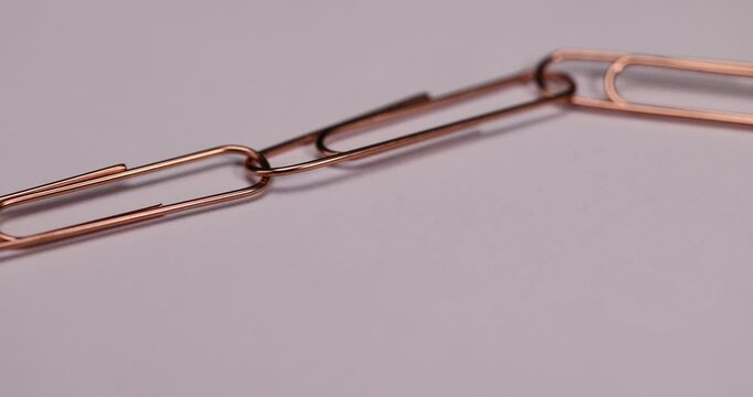 paper clips made of metal for the systematization of documents and paper, large-sized copper paper clips lie on white blank paper